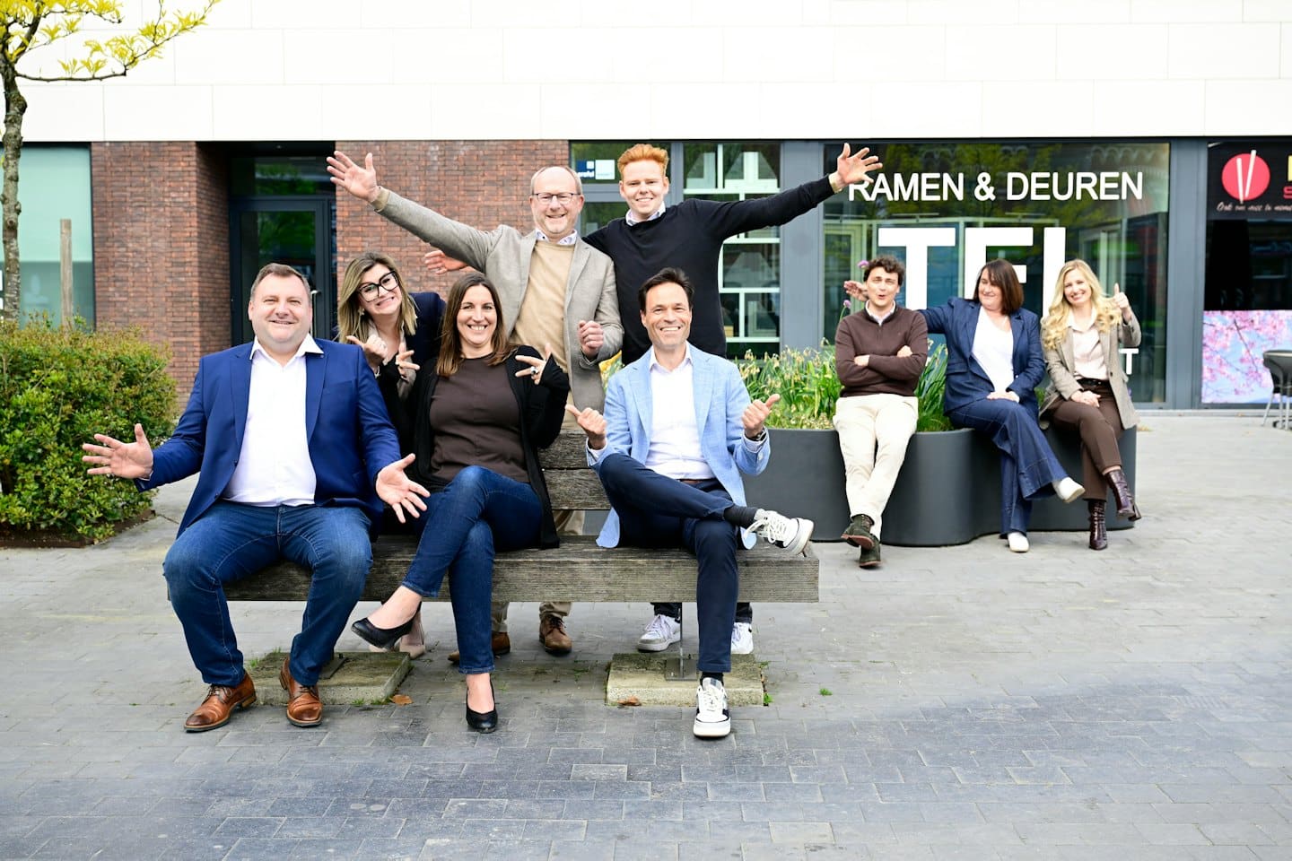 A group of professionals smiling and gesturing outside a modern building.